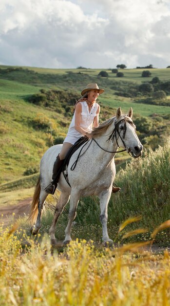 Agricoltore femminile passeggiate a cavallo nella natura all'aperto