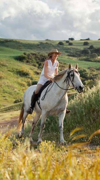 Agricoltore femminile passeggiate a cavallo nella natura all'aperto