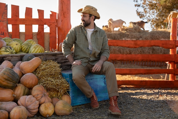 Agricoltore maschio che tiene il raccolto della zucca all'azienda agricola