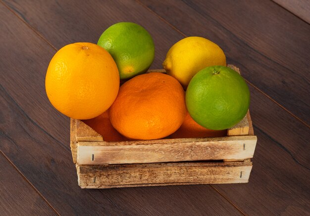 agrumi arancio verde e giallo limone mandarino in scatola di legno sul marrone