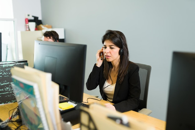 Aiutare i clienti con il supporto tecnico. Bella donna caucasica con un auricolare che lavora su un call center come rappresentante di vendita e parla con un cliente