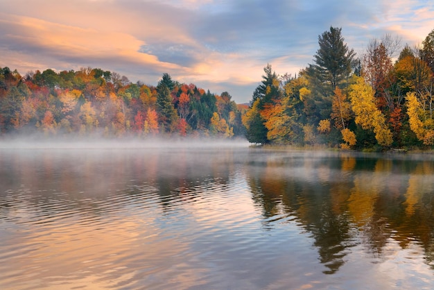 Alba di nebbia del lago con fogliame autunnale e montagne nel New England Stowe