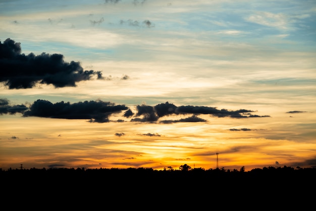 Alba naturale di tramonto sopra il campo o il prato. Cielo drammatico luminoso e terra scura.