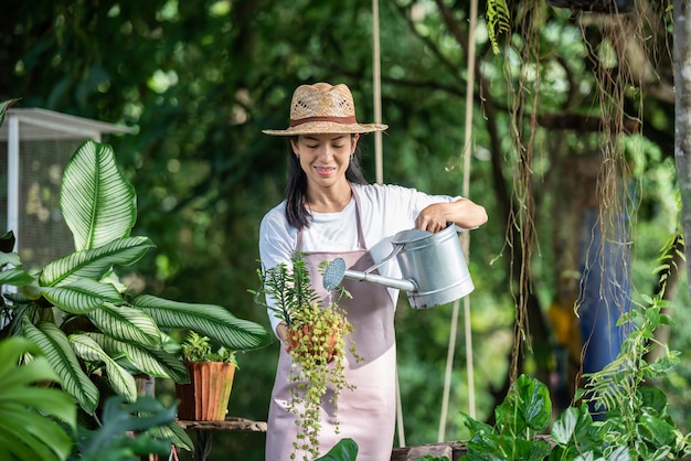 Albero d'innaffiatura della giovane donna graziosa nel giardino al giorno soleggiato di estate. donna giardinaggio fuori nella natura estiva. concetto di agricoltura, giardinaggio, agricoltura e persone.