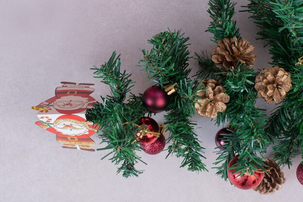 Albero di Natale con palline rosse e pigne nelle quali su superficie grigia