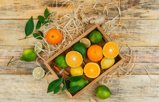 Alcune clementine con lime e mandarino in una cassa di legno su tavola di legno