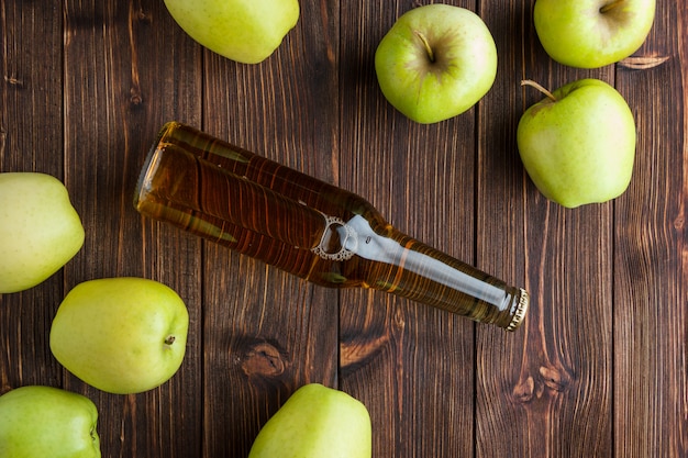 Alcune mele verdi con il succo di mele su fondo di legno, vista superiore.