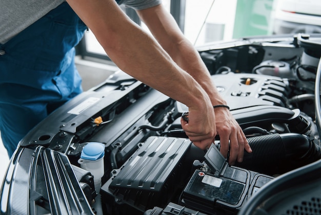 Alcune parti elettroniche. Processo di riparazione dell'auto dopo l'incidente. Uomo che lavora con il motore sotto il cofano