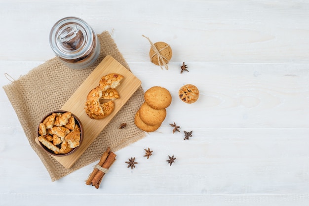 Alcuni biscotti con cannella e chiodi di garofano su un pezzo di sacco sulla superficie bianca