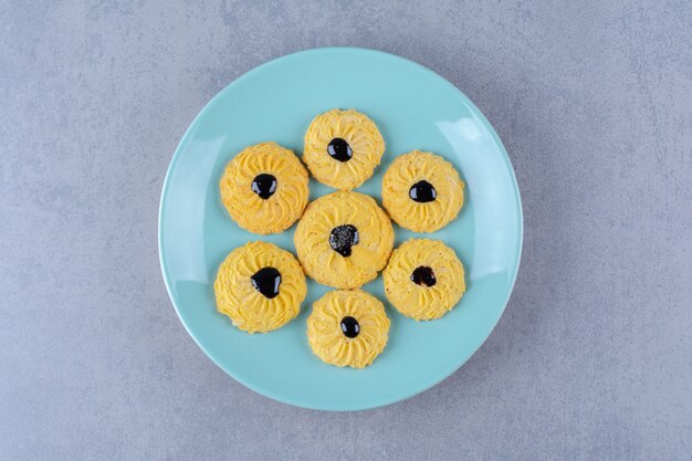 Alcuni dei deliziosi biscotti gialli con sciroppo di cioccolato su un piatto blu.