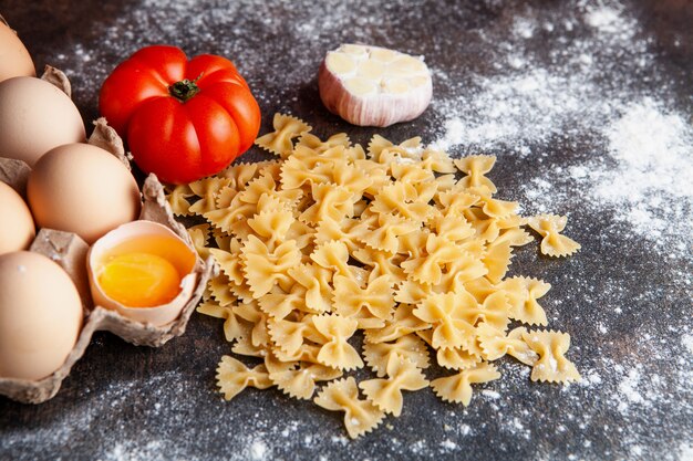 Alcuni maccheroni con le uova, il pomodoro e l'aglio su fondo strutturato scuro, vista superiore.