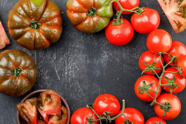 Alcuni pomodori colorati con pomodori freddi sul muro di pietra scura, piatto disteso. copia spazio per il testo