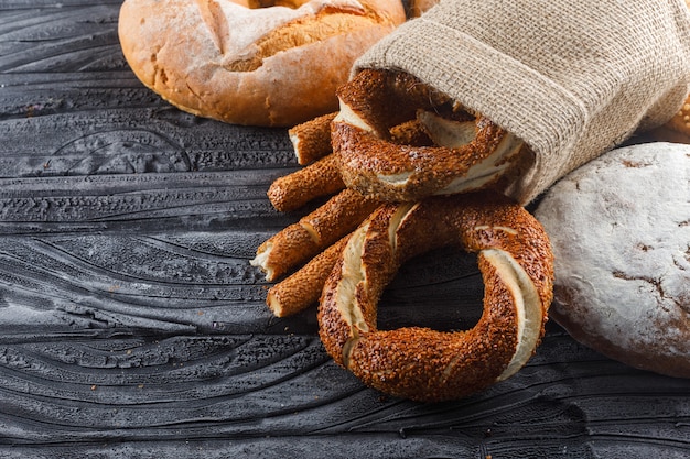 Alcuni prodotti da forno con pane, bagel turco su superficie di legno grigia, vista dell'angolo alto.