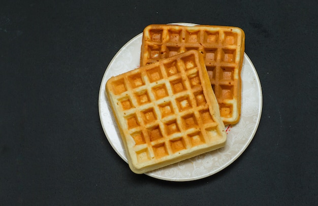 Alcuni waffle in un piatto su scuro, vista dall'alto.