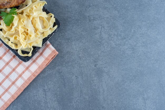 Ali di pollo arrosto e maccheroni sul bordo nero.