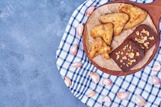 Ali di pollo fritte con pane su una tavola di legno sull'azzurro