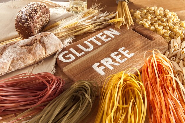 Alimenti senza glutine. Vari pasta, pane e snack su fondo in legno dalla vista dall'alto. Concetto sano e dieta.