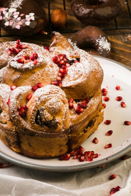 Alimento dolce di recente al forno guarnito con il seme e lo zucchero di polvere del melograno sul piatto bianco