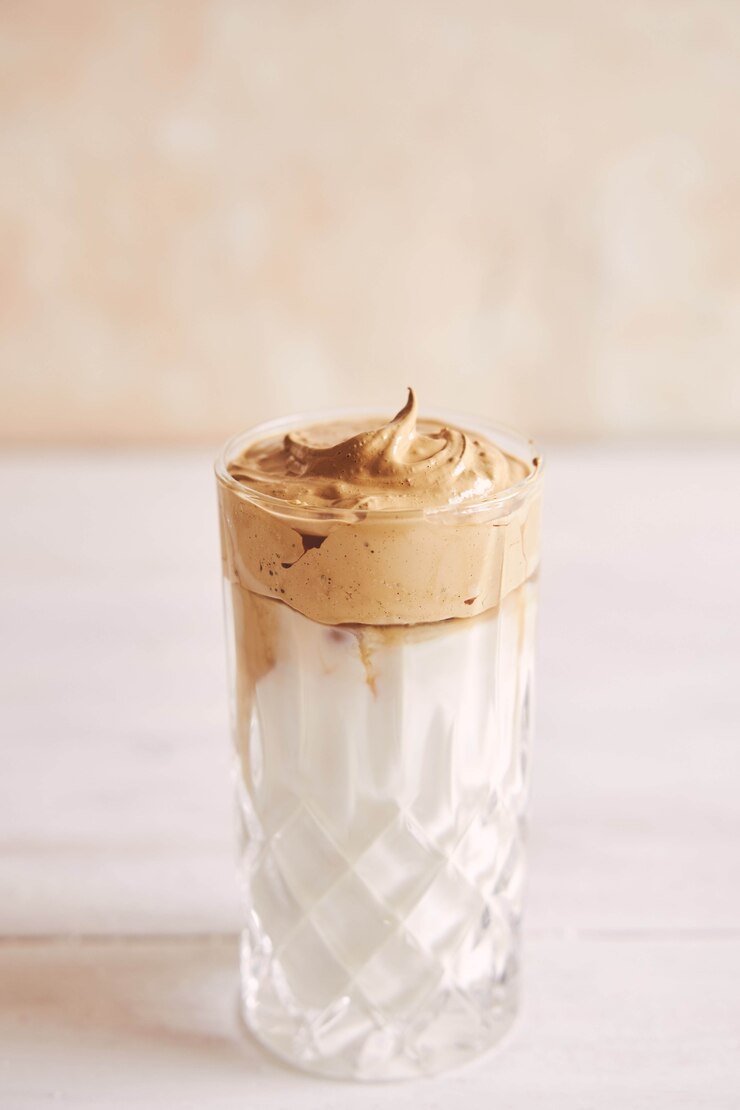 Foto gratuito alla moda delizioso caffè dalgona fresco con latte su un tavolo di legno bianco