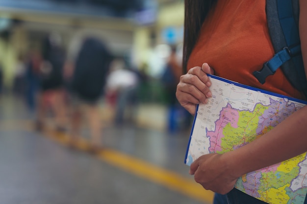 Alle donne piace viaggiare sulla mappa per la stazione ferroviaria.