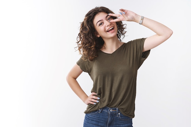 Allegra fiduciosa bella giovane donna hanno il giorno libero tifo divertendosi sentirsi fortunati ottimista spettacolo vittoria o gesto di pace inclinare la testa spensierata sorridente denti ampiamente bianchi, sfondo per studio