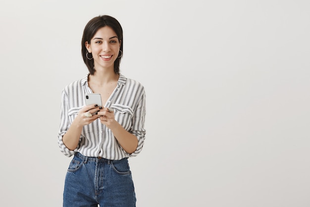 Allegra ragazza attraente utilizzando il telefono cellulare e sorridente