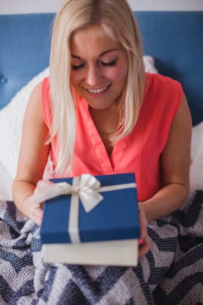 Allegro giovane donna che apre un regalo