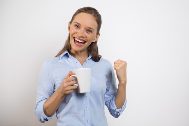 Allegro giovane donna con Tazza di pompaggio pugno