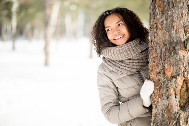 Allegro ragazza latino-americana a albero in inverno