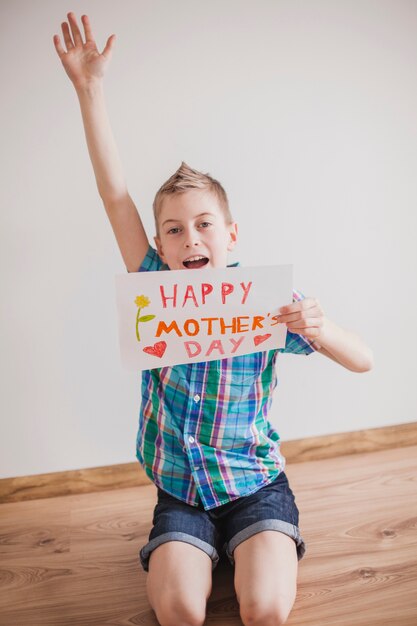 Allegro ragazzo con segno per celebrare la madre