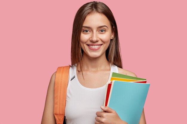 allegro studente in posa contro il muro rosa