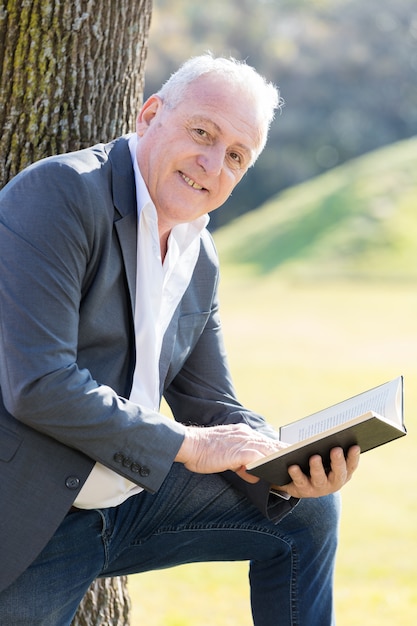 Allegro uomo anziano in posa con un libro aperto