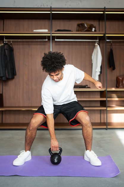 Allenamento dell'uomo con kettlebell sul colpo pieno della stuoia