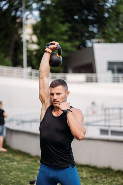 Allenamento sportivo con kettlebell. Foto di un bell'uomo con un buon fisico. Forza e motivazione.