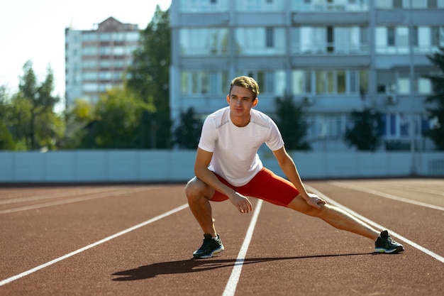 Allenamento sportivo. Giovane sportivo caucasico, atleta maschio, corridore che si esercita da solo allo stadio pubblico