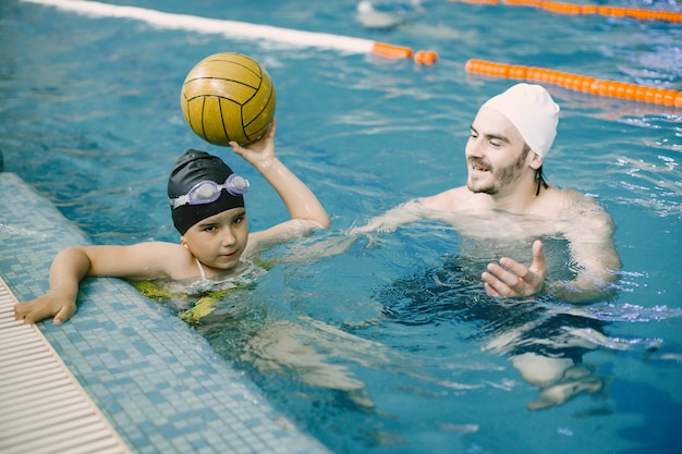 Allenatore che insegna al bambino nella piscina coperta come nuotare e tuffarsi. Lezione di nuoto, sviluppo dei bambini.