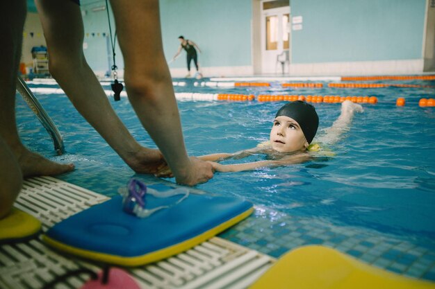 Allenatore che insegna al bambino nella piscina coperta come nuotare e tuffarsi. Lezione di nuoto, sviluppo dei bambini.