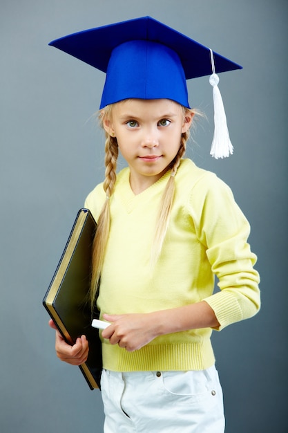 Allievo serio con tappo di laurea e gesso