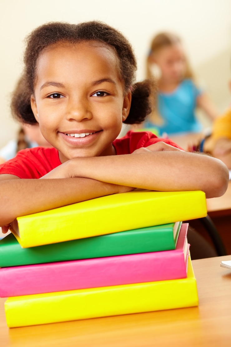 Foto gratuito allievo sorridente appoggiato sui libri impilati