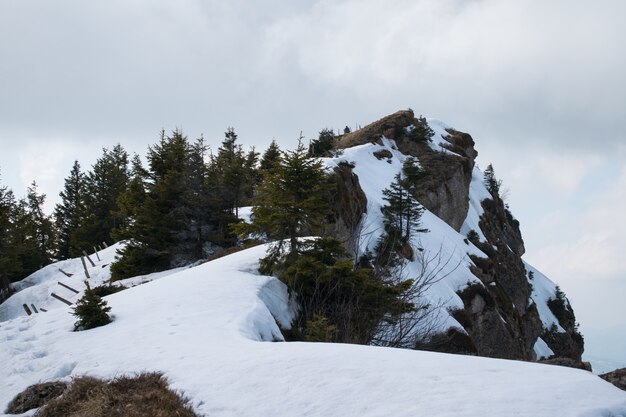 Alta scogliera rocciosa ricoperta di neve sotto un cielo nuvoloso