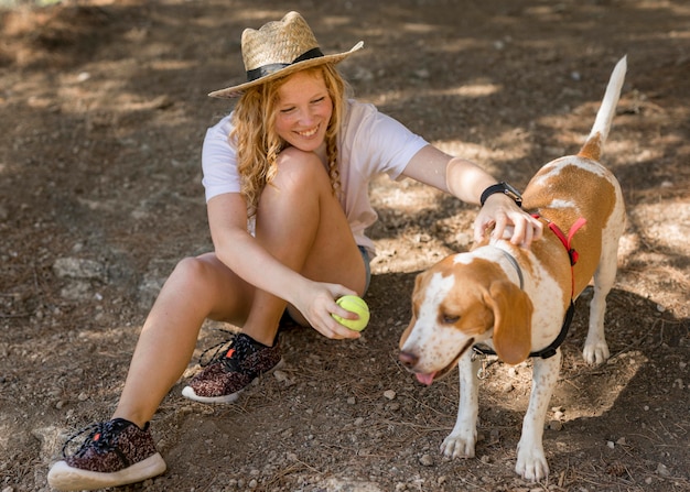 Alta vista donna e il suo cane che giocano