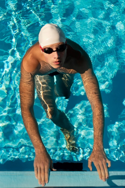 Alto angolo del nuotatore maschio che emerge dalla piscina