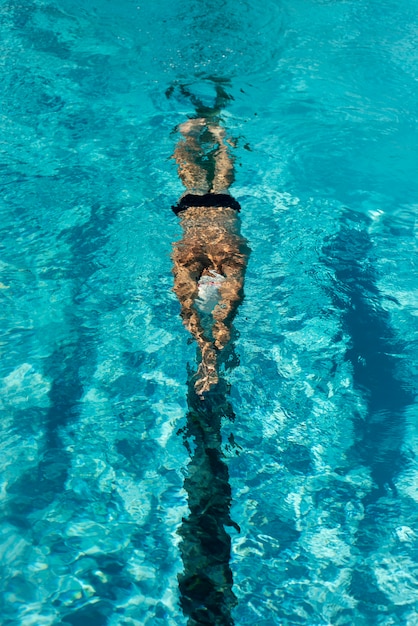 Alto angolo del nuotatore maschio che nuota nella piscina di acqua