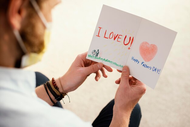 Alto angolo del padre che legge la sua carta per la festa del papà