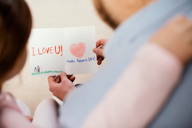 Alto angolo della bambina che dà la carta del padre per la festa del papà