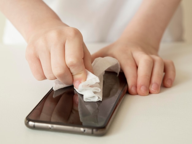 Alto angolo delle mani che disinfettano smartphone