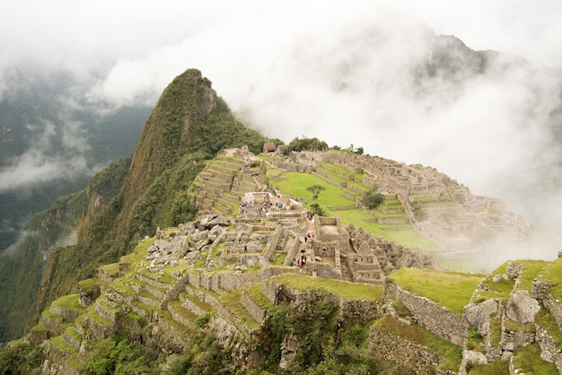 Alto angolo di bella cittadella di Machu Picchu circondato da montagne nebbiose a Urubamba, Perù