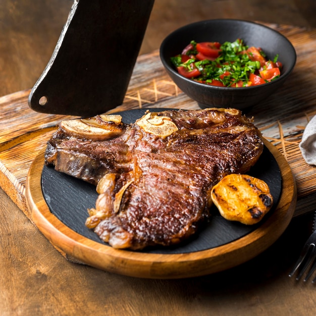 Alto angolo di bistecca sul piatto con insalata e mannaia