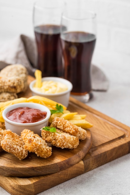 Alto angolo di bocconcini di pollo fritto con salsa e bevande gassate