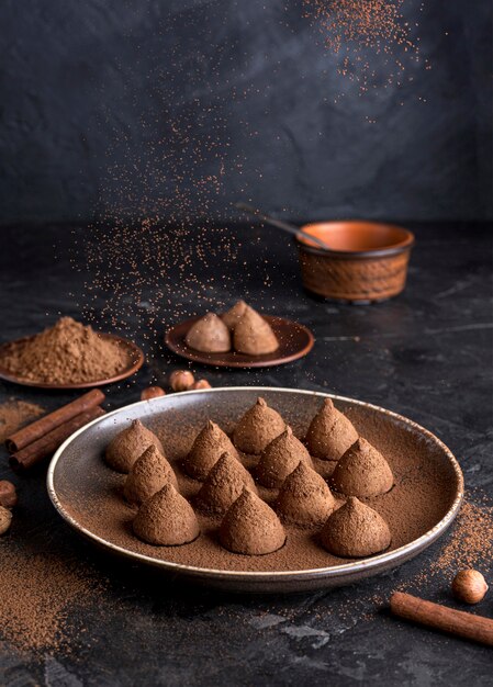 Alto angolo di caramelle al cioccolato con cacao in polvere e bastoncini di cannella